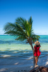 Dominican Republic of Punta Cana, a girl in a hat on the ocean with turquoise water and palm trees.