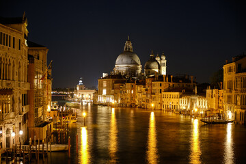 Fototapeta na wymiar Venice, Italy: Night view of Venice Grand Canal with boats and Santa Maria della Salute church on sunset from Ponte dell'Accademia bridge. Venice, Italy