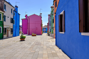 Burano, Venice: Colorful houses of Burano island. Multicolored buildings on fondamenta embankment of narrow water canal with fishing boats and stone bridge, Venice Province, Veneto Region, Italy.
