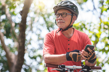 Portrait of Asian Senior Chinese Adult man in helmet holding mobile phone or smartphone while...