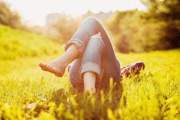 Young hipster girl lying on the grass at sunset summer time