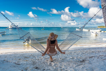 Dominican Republic of Punta Cana, a girl in a hat on the ocean with turquoise water and palm trees.