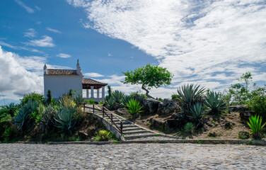 Chapel at the Nossa Senhora da Guia viewpoint, located in Cabo Frio, stone path, surrounding vegetation and beautiful blue sky with clouds.