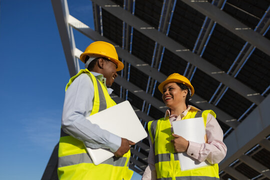 Building workers with folders and laptop discussing panel installation
