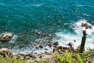 Rocks at Praia dos Foguetes seen from above, close to the city of Cabo Frio, blue sea and surrounding vegetation.