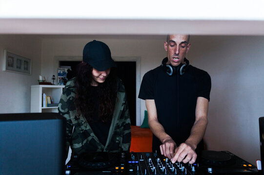 Couple of DJs mixing music on console