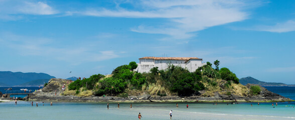 Praia do Forte, with the fort on top of the hill, beautiful beach, lots of rocks and blue sky.