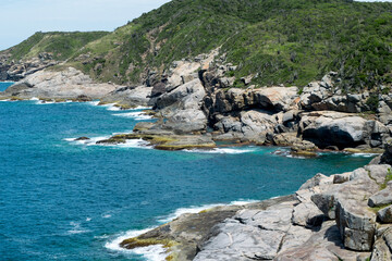 Fototapeta na wymiar Top view of the beautiful beach of Conchas, close to the city of Cabo Frio, with many rocks by the sea, sea of ​​blue waters, with mountains in the background.
