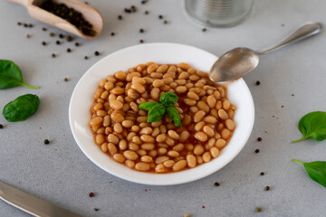 Baked Beans in tomato sauce in a plate against a grey background. Food. Food background