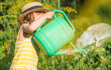Farmer girl in yellow dress. Little vegetables gardener farming in garden. Big green watering can...