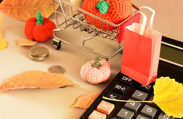 , shopping basket next to coins, orange yarn pumpkins and leaves