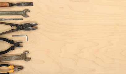 Tools for different repair work, top view. Old tools are laid out in a row on a light wooden table and empty space for text
