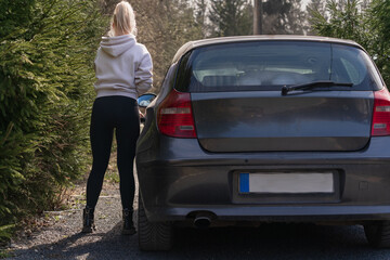 A beautiful athletic girl gets into the car, rear view.