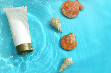 cosmetic product mockup with various seashells in water with water ripples on a blue background.