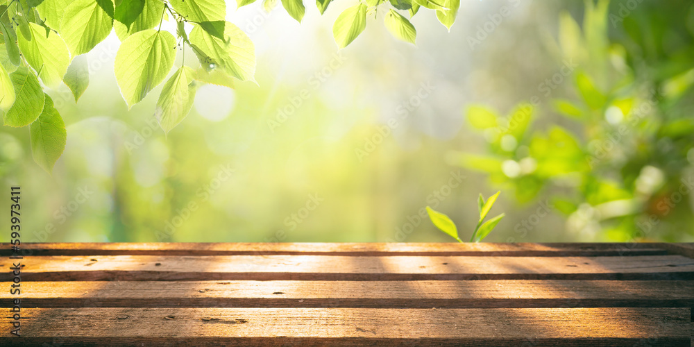Poster spring summer beautiful natural background with green foliage in sunlight and empty wooden table out