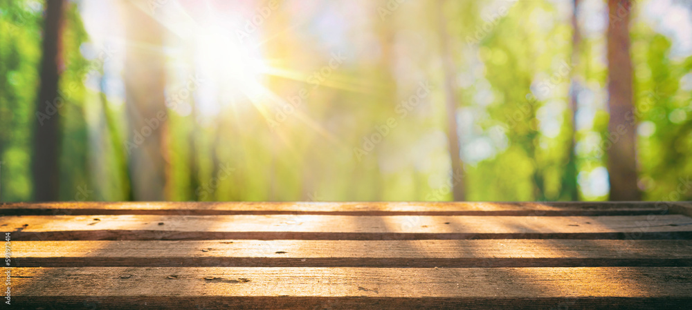 Poster spring summer beautiful nature background with blurred park trees in sunlight and empty wooden table