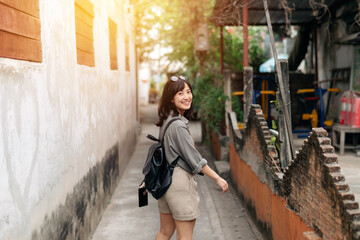 Young Asian woman backpack traveler enjoying street cultural local place and smile. Traveler checking out side streets.