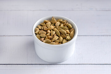 Cardamon seeds bowl. Studio shoot isolated on light background. 45 degree shoot.