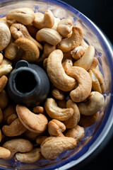 Cashews in the food in the food processor.  Cashews in blender on a black background. Top view. Close-up.
