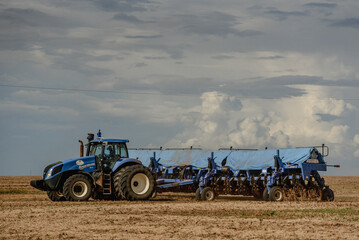 Fototapeta premium tractor in a field and clouded sky 