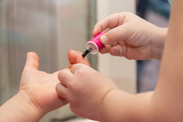 Little girls paint each other's nails with baby nail polish.