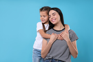 Happy woman with her cute daughter on light blue background, space for text. Mother's day celebration