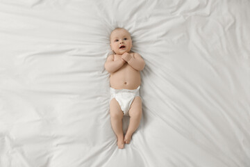 Cute little baby in diaper lying on white bed, top view - obrazy, fototapety, plakaty
