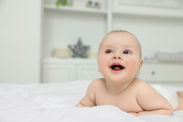 Cute baby lying on white bed at home, space for text