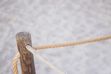 Formentera. Holzpfosten und Seil. Weißer Sand im Hintergrund.