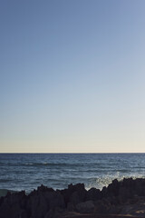 Formentera. Blauer Himmel und Meer. Steinerne Küste im Vordergrund.