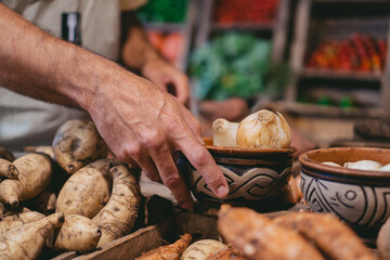 Detail shot of a male hand holding a handmade clay bowl with onions in a greengrocer's shop.