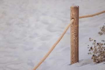 Formentera. Holzpfahl und Seil. Weißer Sand im Hintergrund.