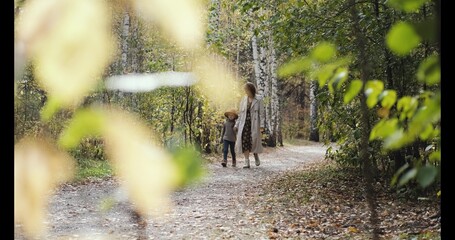 Hello September. A young mother and little daughter walk in the city park in autumn.