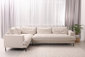 Comfortable sofa and window with beautiful curtains in room. Interior design
