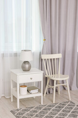 Fototapeta na wymiar Stylish room interior with comfortable chair, table and beautiful window curtains