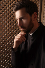 Catholic priest wearing cassock in confessional booth