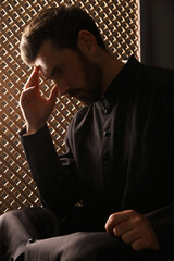 Catholic priest wearing cassock in confessional booth - obrazy, fototapety, plakaty