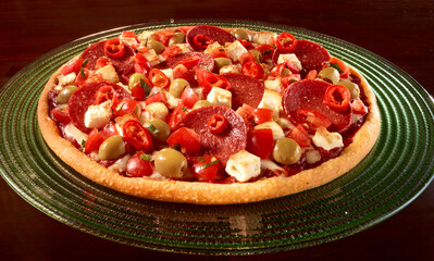 Pizza mit Salami und Oliven mit Feta und Chili auf grünem Teller