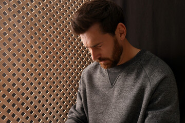 Upset man listening to priest during confession in booth, space for text