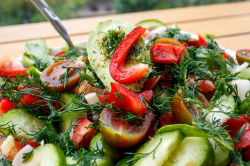 Close-up of fresh vegetable salad from cherry tomatoes, cucumbers, bell peppers and avocado