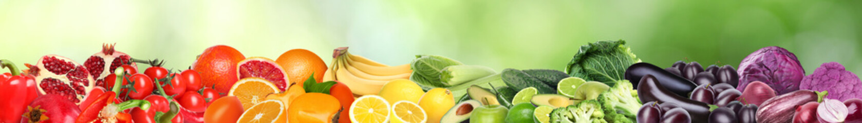 Many different fresh fruits and vegetables against blurred green background. Banner design
