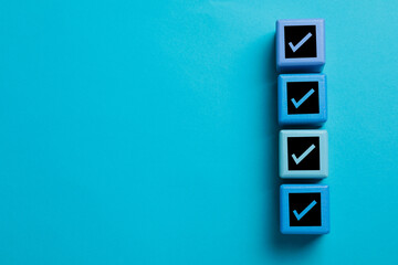 Cubes with check marks on light blue background, top view. Space for text