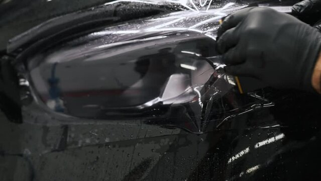 Smoothing tinting film after putting it on a car headlight. High quality 4k footage