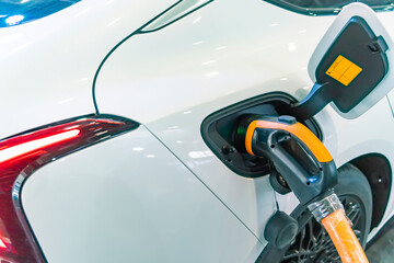 Electric car charging on parking lot with electric car charging station.