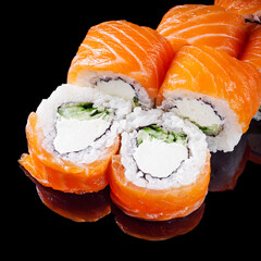 sushi roll with salmon cream cheese philadelphia cucumber on a black mirror background