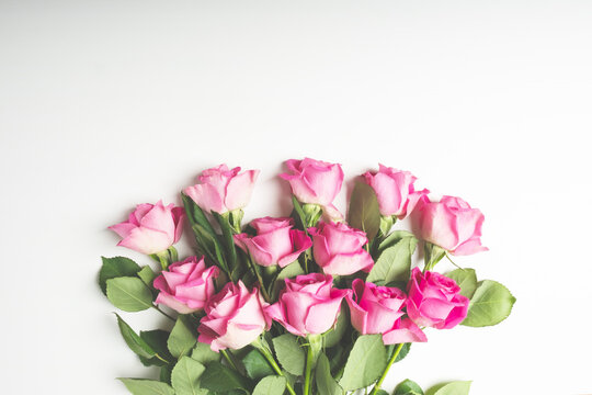 Heap of beautiful fresh pink roses in full bloom on white background. Bouquet of flowers, flat lay. Valentine's day or Mother's day card.