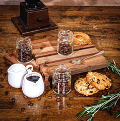 many coffee beans placed around and sugar on a wooden table in a warm, light atmosphere, on dark background, with copy space.