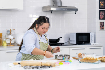 Asian person with Down syndrome cooking at kitchen