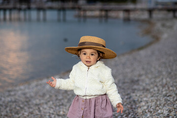 stylish bearded man with curly hair in linen shirt and fashionable sunglasses posing at the italian Garda lake beach at the sunset 