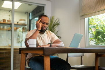 Obraz premium Happy African American man wearing casual clothes working in his home